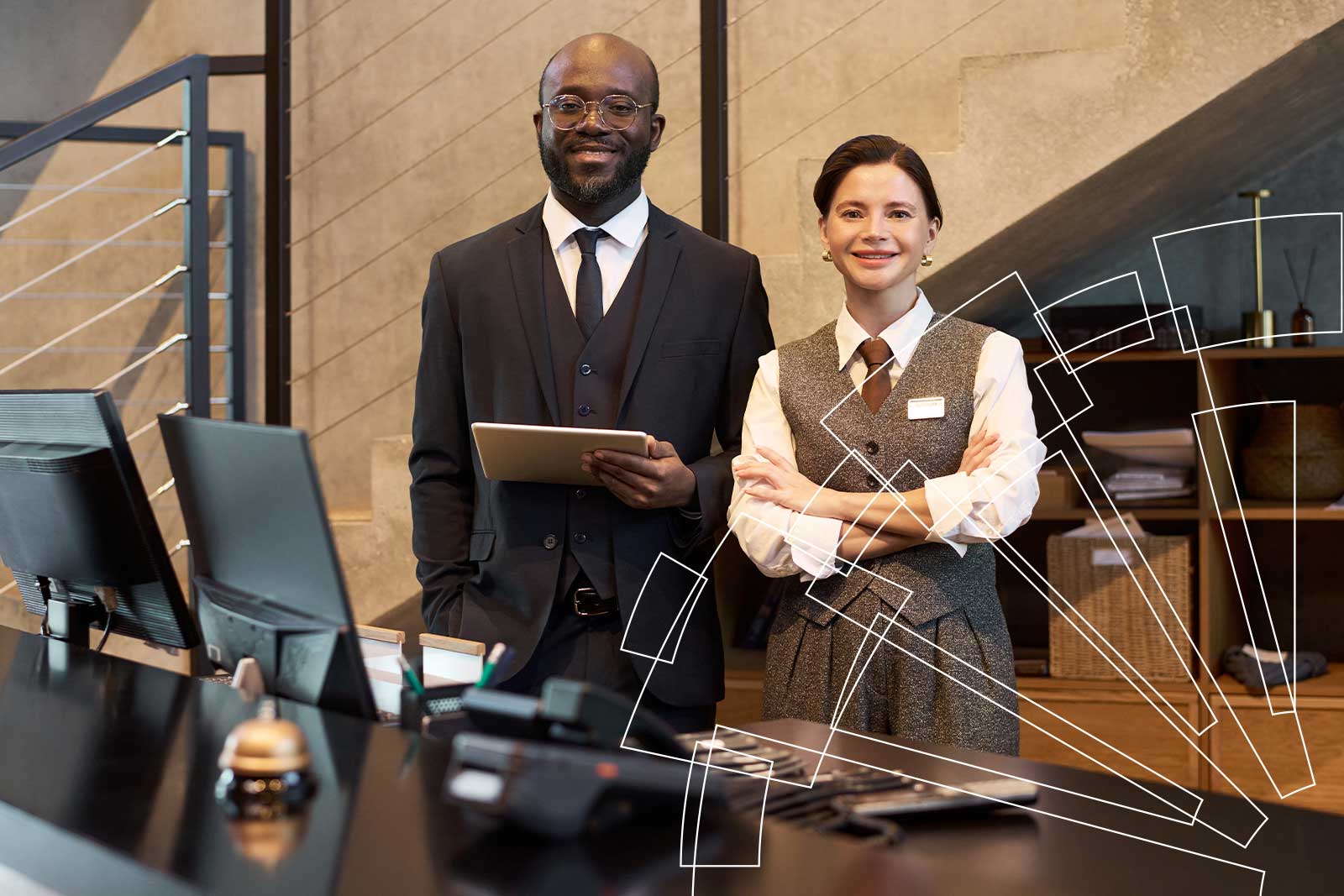 Dos recepcionistas sonrientes detrás del mostrador de un hotel